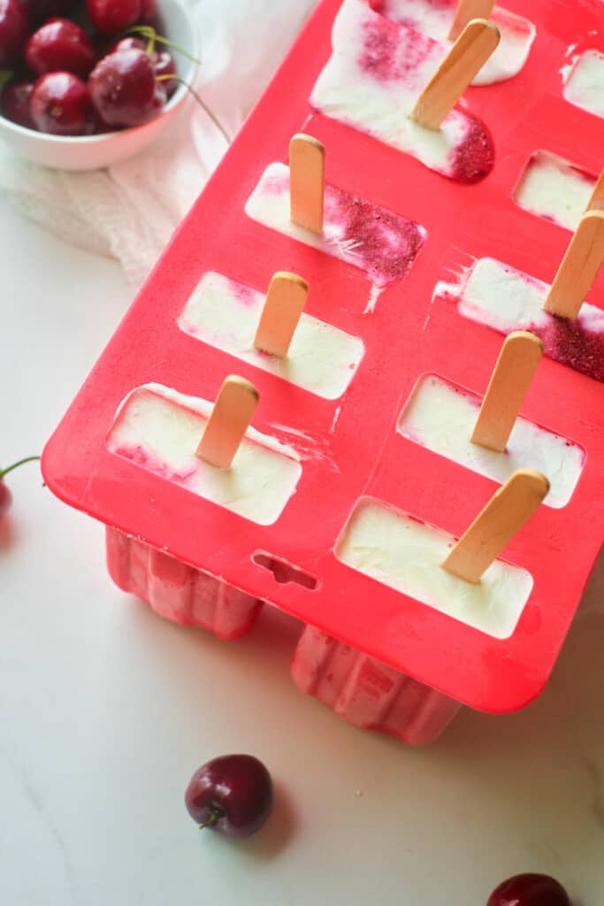 Put the popsicle sticks in the cherry coconut mixture and freeze