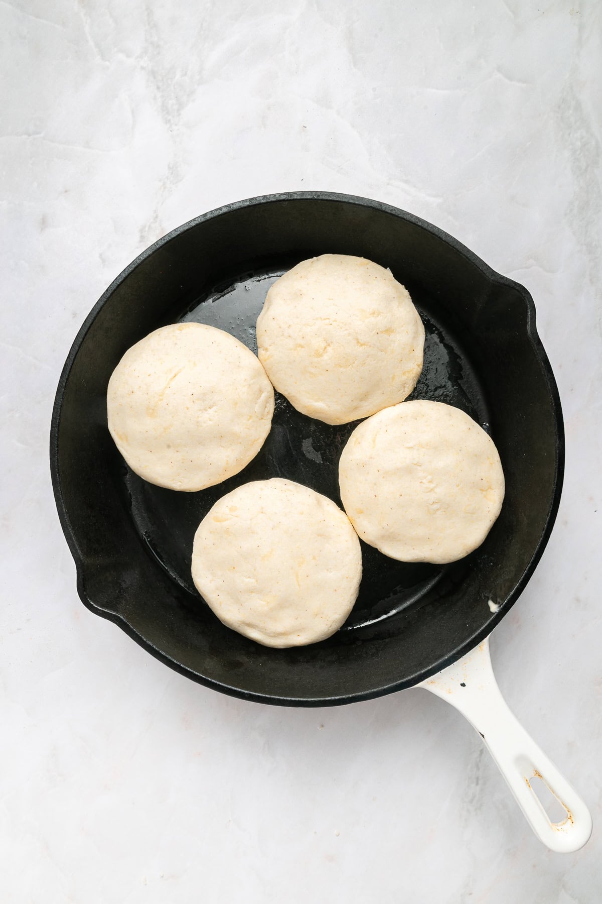 Cooking arepas in an iron cast skillet.