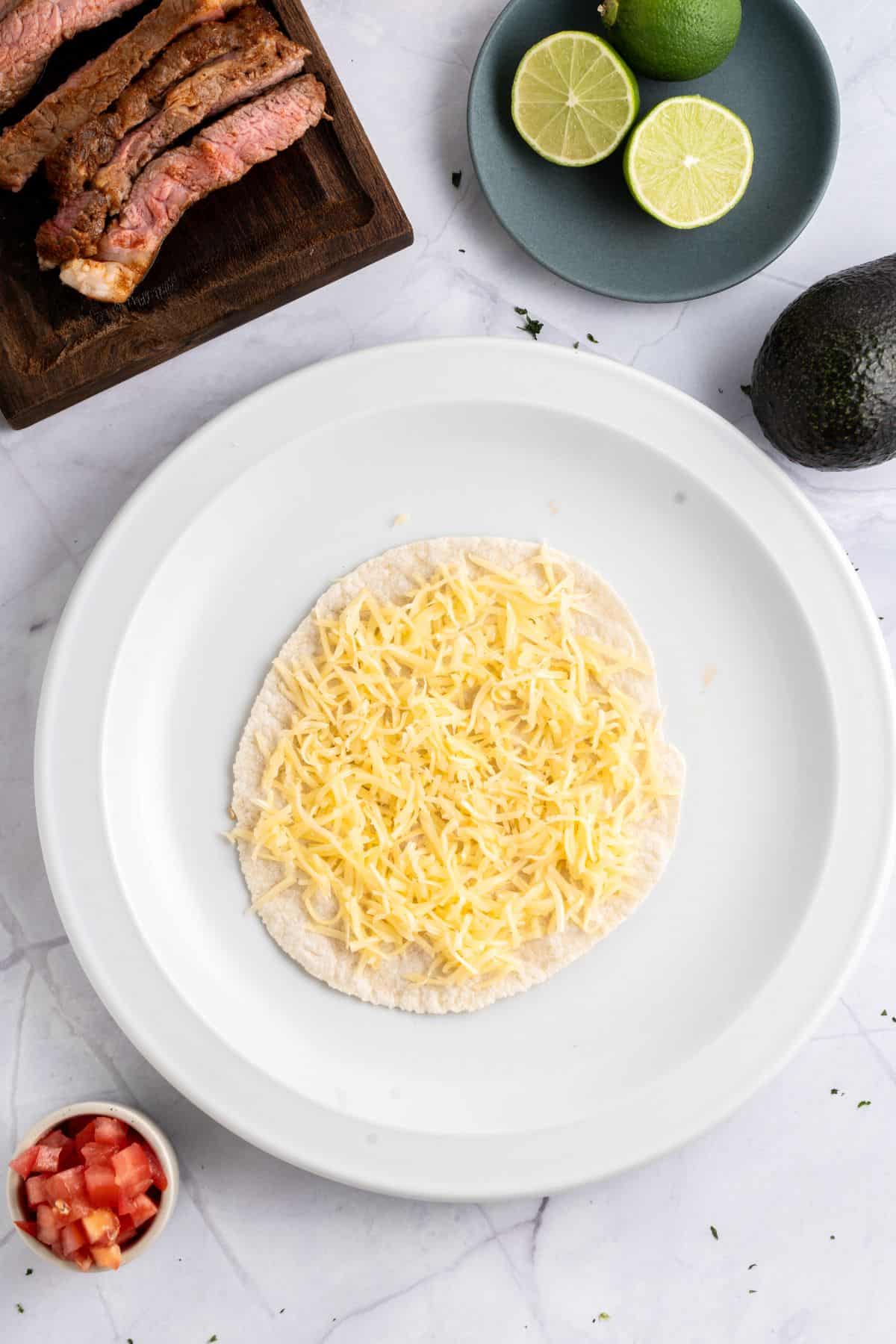 Adding shredded cheese to a tortilla.