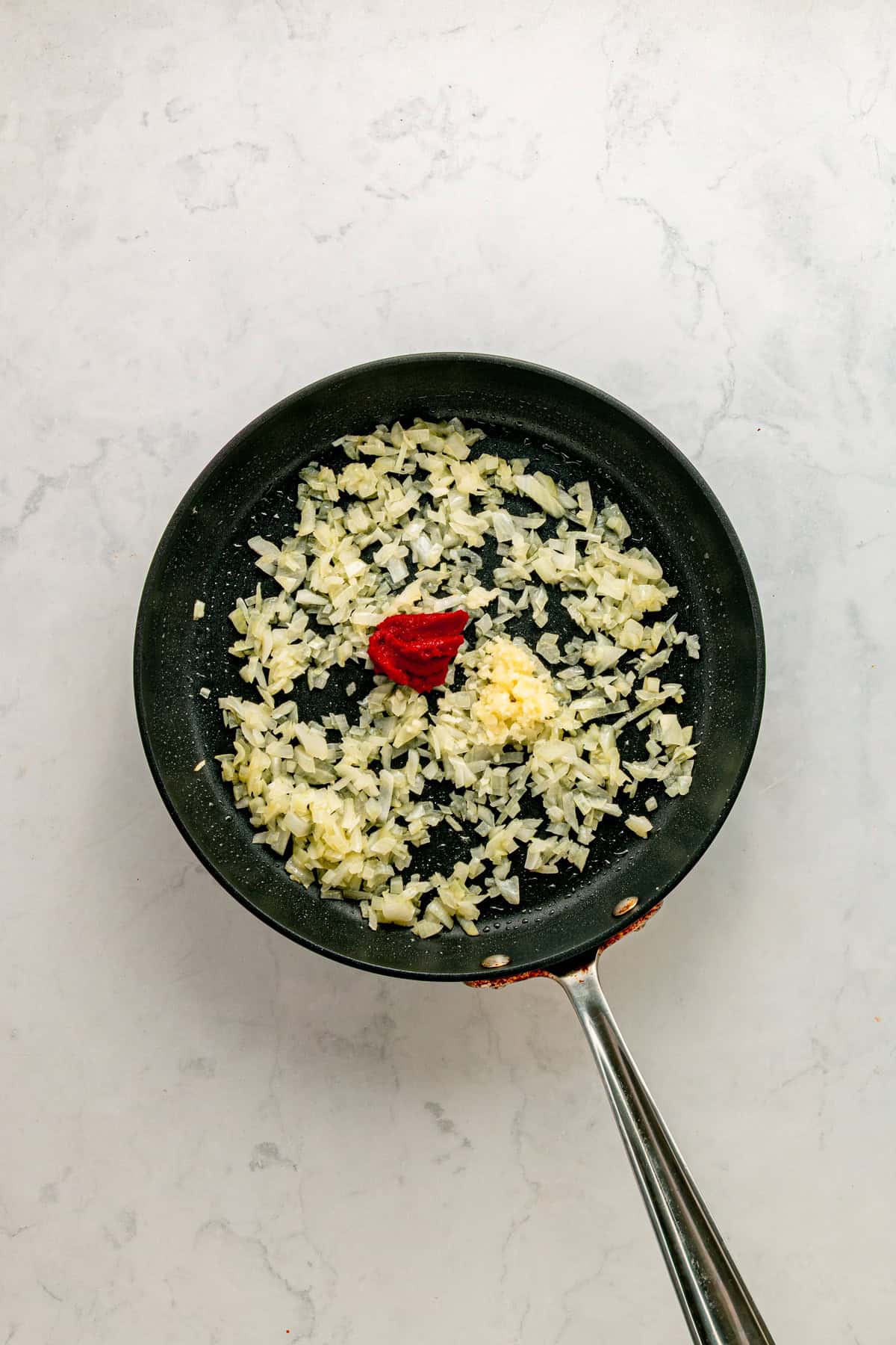 Adding tomato paste and minced garlic.